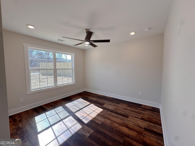 empty room with dark wood-style flooring, recessed lighting, and baseboards