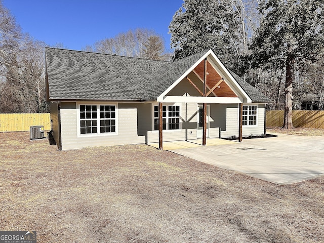 view of front of property featuring central AC unit, a patio area, fence, and a shingled roof