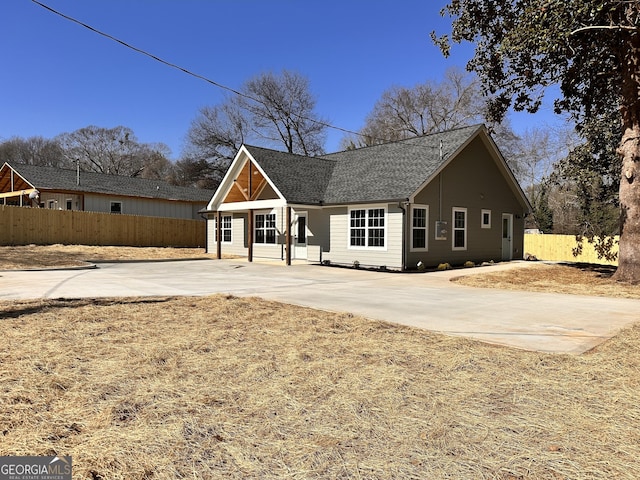 view of front of house with roof with shingles and fence