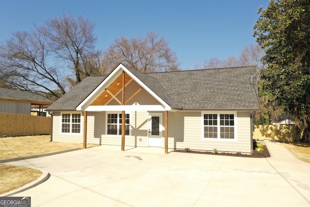 back of property with a shingled roof, a patio area, and fence