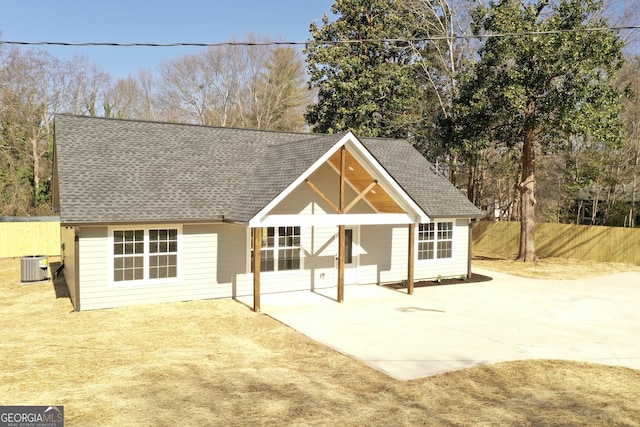 exterior space featuring a patio area, roof with shingles, fence, and central AC unit