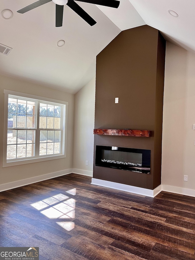 unfurnished living room with lofted ceiling, dark wood-type flooring, a glass covered fireplace, and visible vents