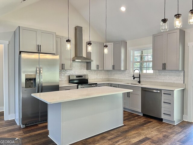 kitchen featuring wall chimney exhaust hood, a center island, hanging light fixtures, appliances with stainless steel finishes, and light stone countertops