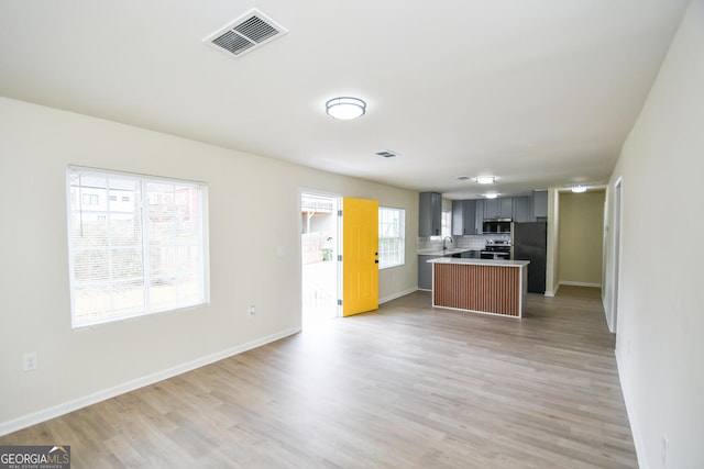 kitchen with appliances with stainless steel finishes, sink, gray cabinetry, and light wood-type flooring