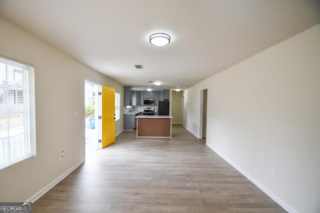 kitchen with stainless steel appliances, a kitchen island, hardwood / wood-style floors, and decorative backsplash