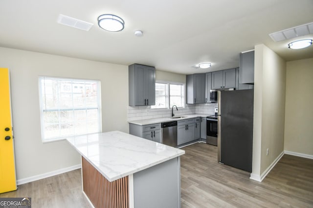 kitchen featuring gray cabinetry, sink, stainless steel appliances, and a center island