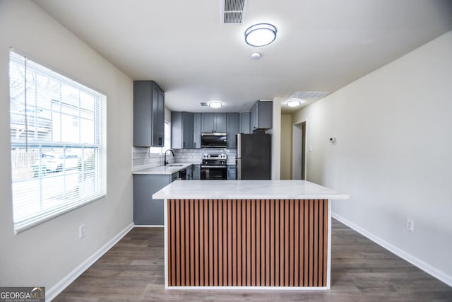 kitchen with gray cabinets, appliances with stainless steel finishes, dark hardwood / wood-style floors, tasteful backsplash, and sink