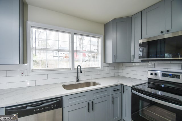 kitchen with tasteful backsplash, sink, gray cabinets, and appliances with stainless steel finishes