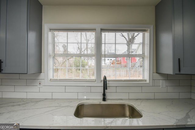 interior space featuring gray cabinets, light stone countertops, and sink