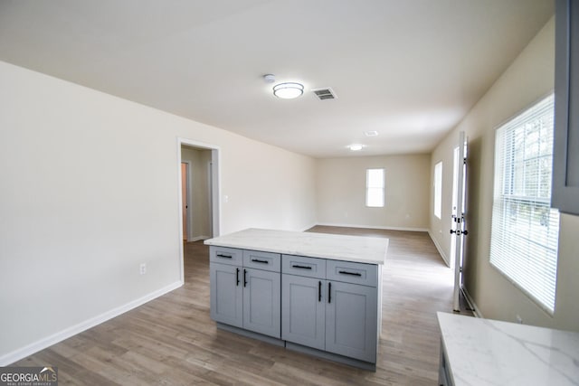 kitchen featuring light stone counters, gray cabinets, and hardwood / wood-style flooring