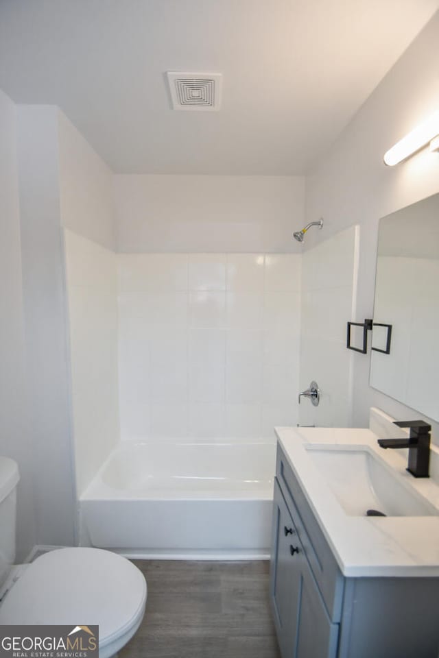 full bathroom featuring vanity, wood-type flooring, shower / bathtub combination, and toilet