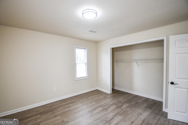 unfurnished bedroom with hardwood / wood-style flooring and a closet