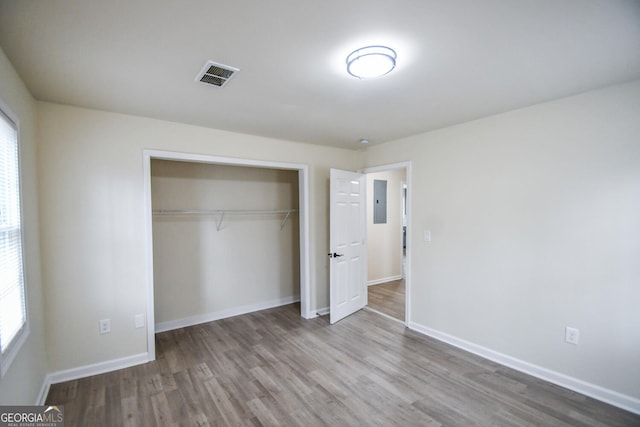 unfurnished bedroom with wood-type flooring, electric panel, and a closet