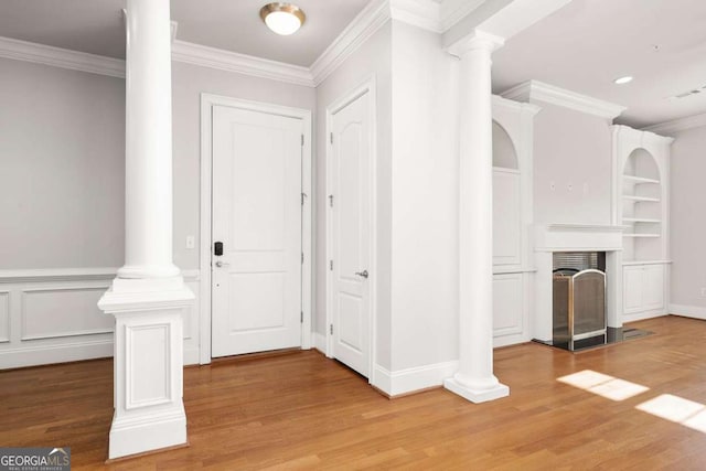 entrance foyer featuring crown molding, wood-type flooring, and decorative columns