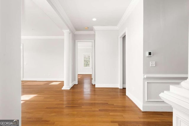 interior space featuring crown molding, decorative columns, and hardwood / wood-style flooring