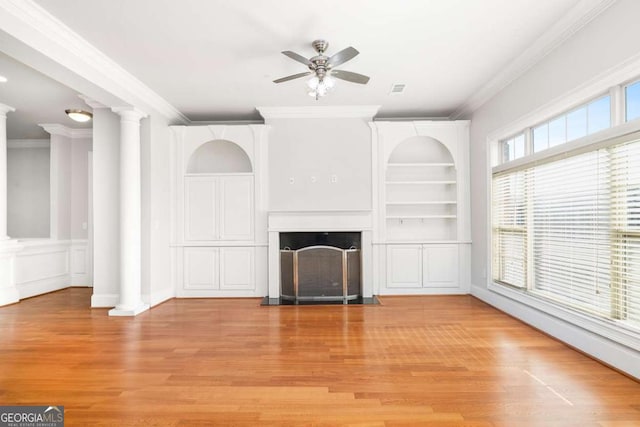 unfurnished living room featuring crown molding, light hardwood / wood-style flooring, built in features, ceiling fan, and decorative columns