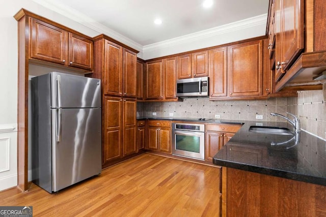 kitchen with sink, stainless steel appliances, light hardwood / wood-style floors, and dark stone counters