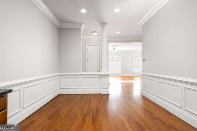 unfurnished room with decorative columns, ceiling fan, crown molding, and light hardwood / wood-style floors