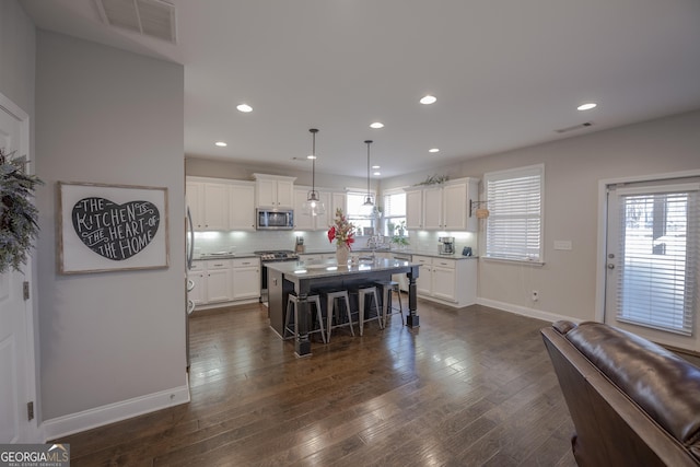 kitchen with a center island, a breakfast bar area, light countertops, hanging light fixtures, and appliances with stainless steel finishes