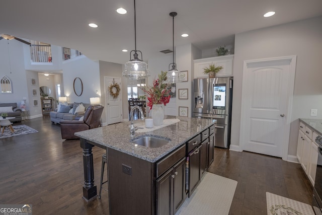 kitchen with a sink, a kitchen breakfast bar, white cabinets, dark brown cabinets, and stainless steel fridge