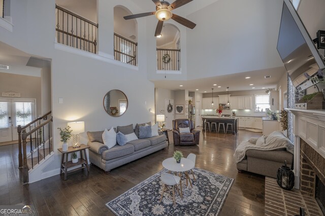 living room featuring dark wood-style floors, a brick fireplace, a healthy amount of sunlight, and stairway