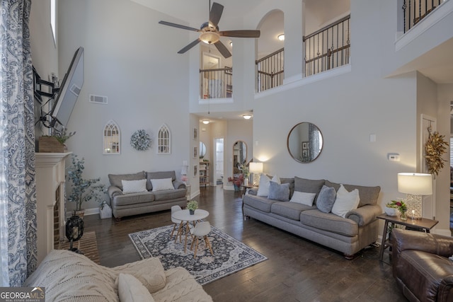 living area with baseboards, visible vents, ceiling fan, dark wood-style flooring, and a fireplace