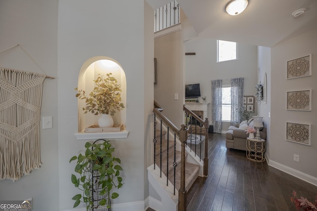 interior space with stairway, dark wood-style flooring, a towering ceiling, and baseboards