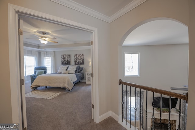 carpeted bedroom with baseboards, arched walkways, ceiling fan, and crown molding