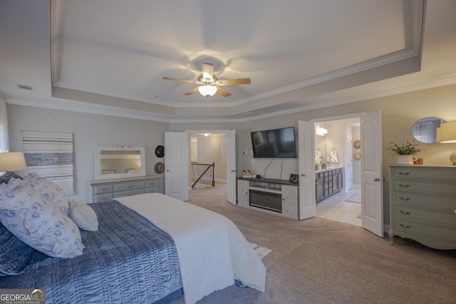 bedroom with light carpet, visible vents, a ceiling fan, ornamental molding, and a tray ceiling