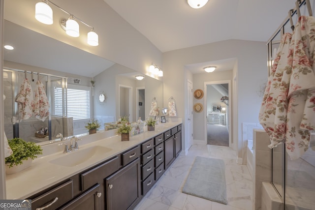 bathroom featuring double vanity, marble finish floor, vaulted ceiling, a shower stall, and a sink