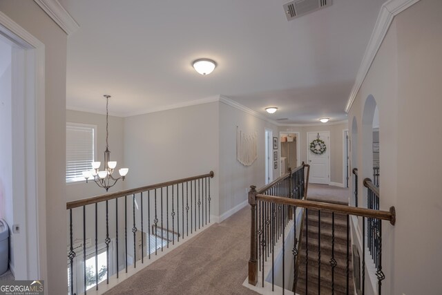 hall with ornamental molding, visible vents, light colored carpet, and an upstairs landing