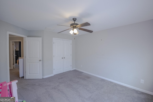 unfurnished bedroom featuring light carpet, a closet, a ceiling fan, and baseboards