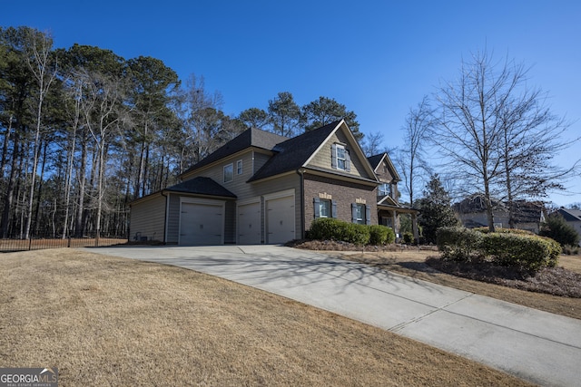 view of property exterior with an attached garage, brick siding, fence, concrete driveway, and a lawn