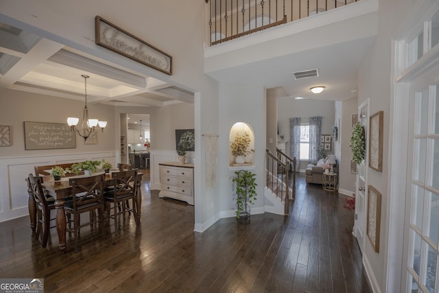 foyer featuring visible vents, coffered ceiling, dark wood-type flooring, and a chandelier