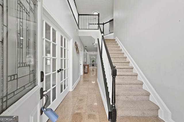 stairway featuring french doors and a high ceiling