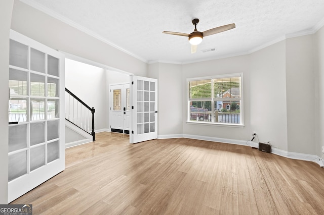 spare room featuring ceiling fan, ornamental molding, light hardwood / wood-style floors, a textured ceiling, and french doors