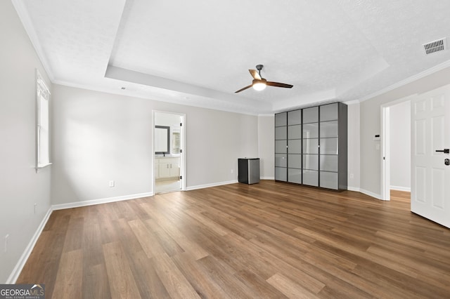 unfurnished living room featuring ceiling fan, wood-type flooring, a raised ceiling, and a textured ceiling