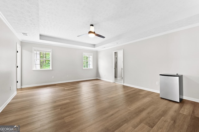 empty room with a raised ceiling, dark hardwood / wood-style floors, and a textured ceiling