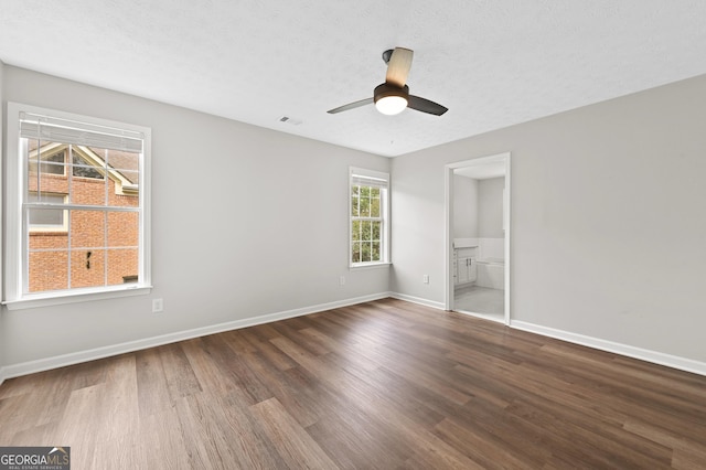 unfurnished bedroom featuring ceiling fan, dark hardwood / wood-style floors, a textured ceiling, and ensuite bath