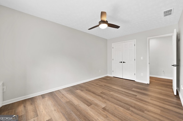 unfurnished bedroom with hardwood / wood-style floors, a closet, and ceiling fan