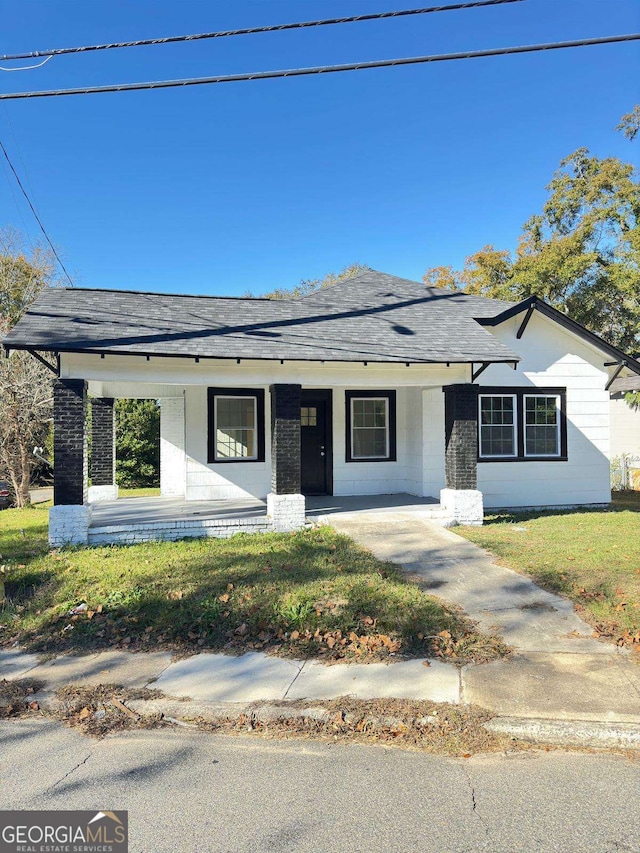 ranch-style home featuring a front lawn and covered porch