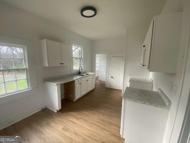 kitchen featuring white cabinetry, plenty of natural light, sink, and light wood-type flooring