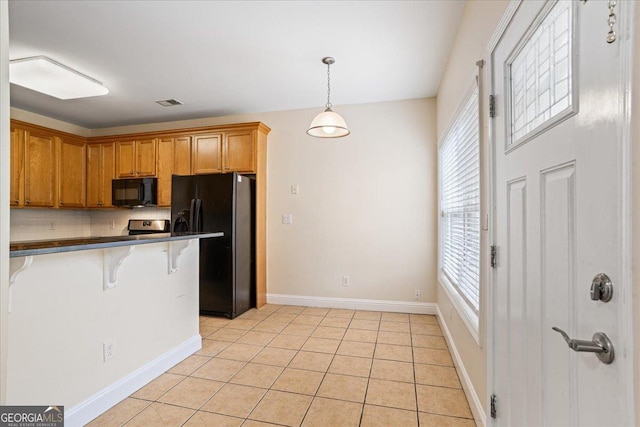 kitchen with a breakfast bar area, decorative backsplash, hanging light fixtures, light tile patterned floors, and black appliances