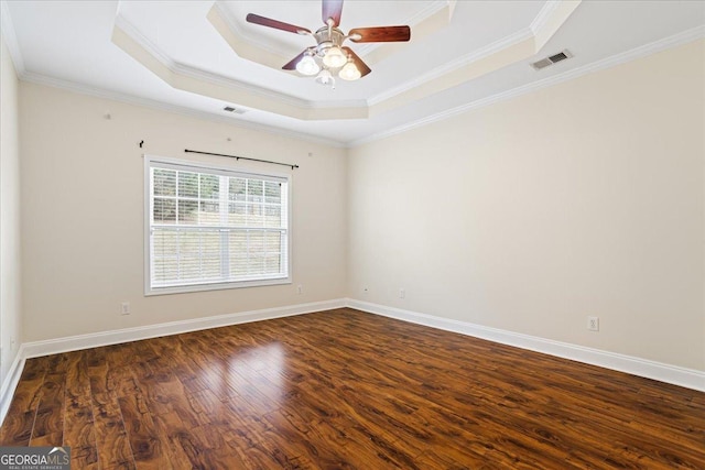 empty room featuring a raised ceiling, ornamental molding, dark hardwood / wood-style floors, and ceiling fan