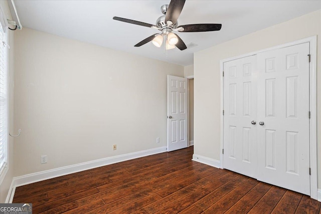 unfurnished bedroom with dark hardwood / wood-style flooring, a closet, and ceiling fan