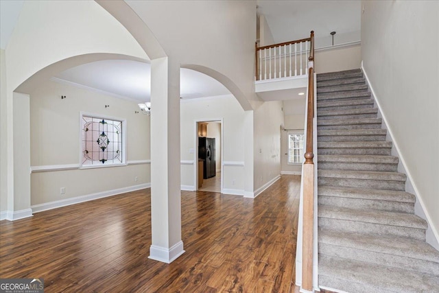 entryway featuring dark hardwood / wood-style flooring, a towering ceiling, ornamental molding, and a healthy amount of sunlight