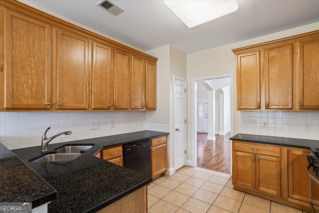 kitchen featuring sink, dishwasher, light tile patterned flooring, decorative backsplash, and dark stone counters