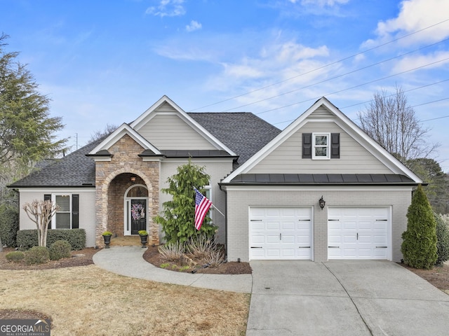 view of front of house featuring brick siding, a shingled roof, a standing seam roof, a garage, and driveway