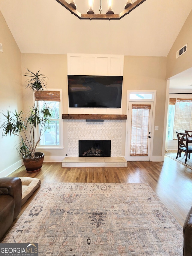 living room with plenty of natural light, visible vents, wood finished floors, and a tile fireplace