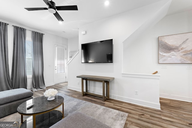 living room featuring ceiling fan, baseboards, and wood finished floors